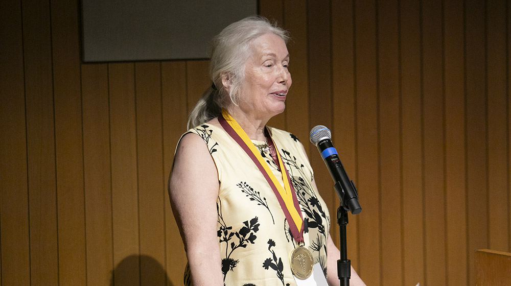 2025 Stritch Medalist Dr. Eva Bading speaking into a microphone at the award ceremony